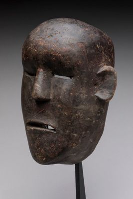 sculpture représentant le visage d'un homme, posée sur un socle, avec un fond gris