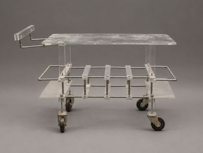 une image représentant un chariot en verre et en métal muni de roues