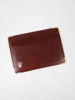 un porte-cartes en cuir marron orné d'un emblème en forme de couronne sur le devant
