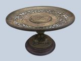 a bronze plate on a stand with a flower design on it