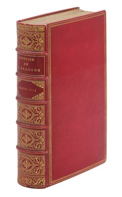 un vieux livre à la couverture rouge et à la bordure dorée