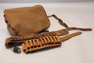 une photo d'un sac en cuir marron contenant un fusil de chasse, posé sur une surface blanche