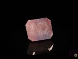 un gros plan d'un quartz rose posé sur une surface noire