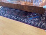 a large wooden table with a glass top on a rug