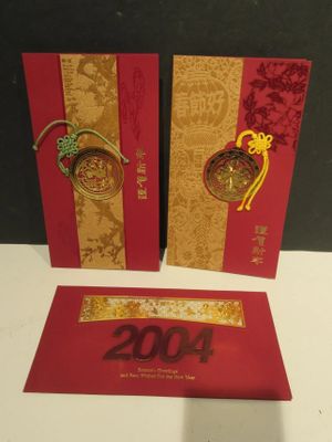 two red and gold chinese new year cards on a white table