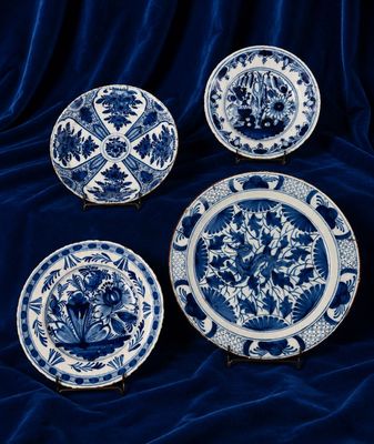 quatre assiettes bleues et blanches ornées de motifs floraux, posées sur une nappe bleue