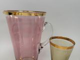 a pink pitcher and a gold cup on a white table