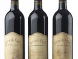 three bottles of wine are lined up on a white surface