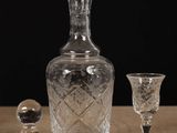 a glass bottle and two wine glasses on a table
