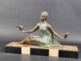 bronze statue of a woman sitting on a marble block holding two birds