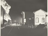 photographie en noir et blanc d'un train entrant en gare de nuit
