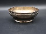 an antique silver bowl on a black surface with a black background