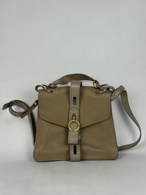 le petit sac beige est posé sur une surface blanche