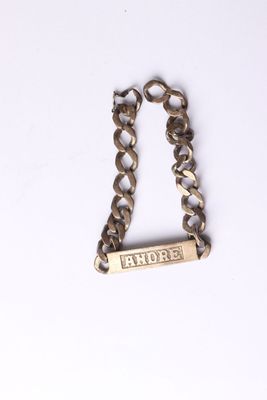 silver chain bracelet with a nameplate on it on a white surface