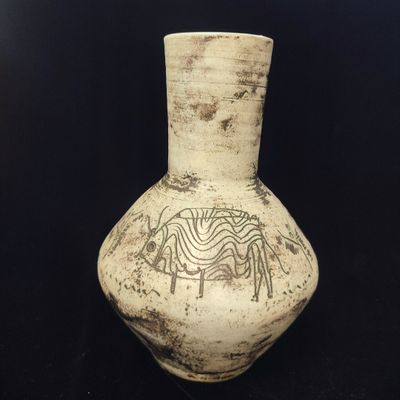 un vase blanc orné d'un motif sur fond noir