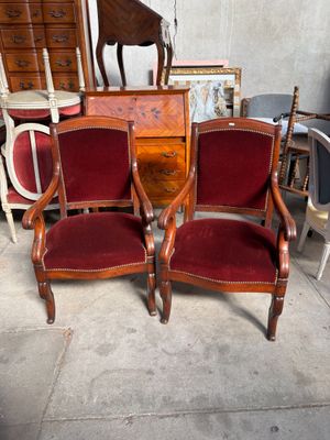 une paire de fauteuils recouverts de velours rouge, placés devant une commode