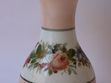 un vase blanc avec des fleurs roses sur une table