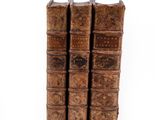 three old books sitting on top of each other on a white surface