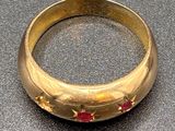 an image of a gold ring with red stones on a table