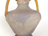 a vase with a yellow handle on a white surface
