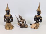 trois statues en bronze représentant une femme et un homme assis sur un rocher