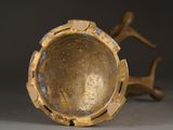 a gold vase sitting on a table with a bird on it