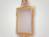 un miroir à cadre doré orné d'un motif décoratif accroché au mur