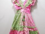pink and green dress hanging on a hanger against a white wall