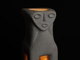 a small gray ceramic lamp with a face on it