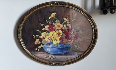 un tableau représentant des fleurs dans un vase bleu accroché au mur