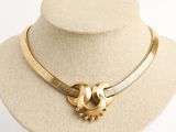 collier doré avec deux boucles et un fermoir, posé sur le cou d'un mannequin