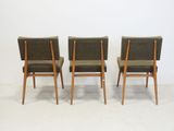 four mid century style chairs in a row against a white wall