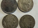 four different british coins sitting on top of a white surface