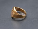 a close up of a gold signet ring on a black surface