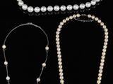 three pearl necklaces and a bracelet on a black background