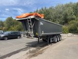 un camion-benne garé sur un parking, avec une voiture en arrière-plan