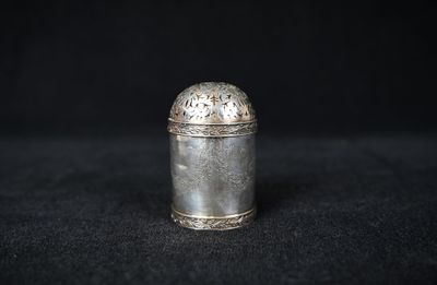 an old silver container sitting on top of a black surface