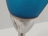 a blue glass vase with a silver stem on a table