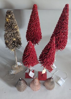 three small christmas trees with red and gold tinsels on a white surface