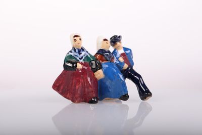 three figurines of people sitting on a white surface