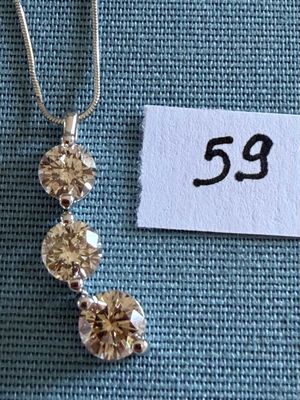 un gros plan d'un collier posé sur un tissu bleu, avec une étiquette de prix