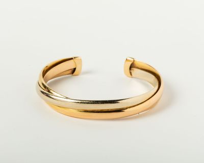 a gold cuff bracelet with a curved design on a white background