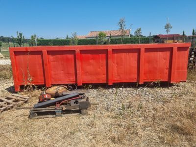 une benne rouge posée au milieu d'un champ