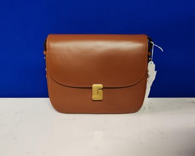 un sac à main marron posé sur une table près d'un mur bleu