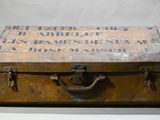 an old suitcase sitting on a table with a sign on it