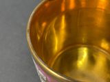 a gold cup with a purple and white design on it