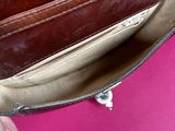 the inside of a brown purse with a hand holding it