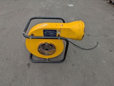 a yellow blower sitting on the ground in a parking lot