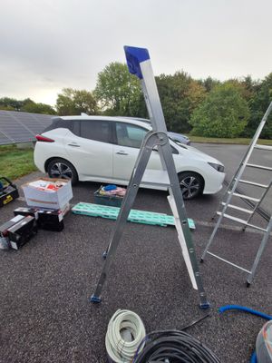 a white car parked in a parking lot next to a ladder