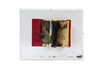 an open book with a red cover sitting on top of a white surface